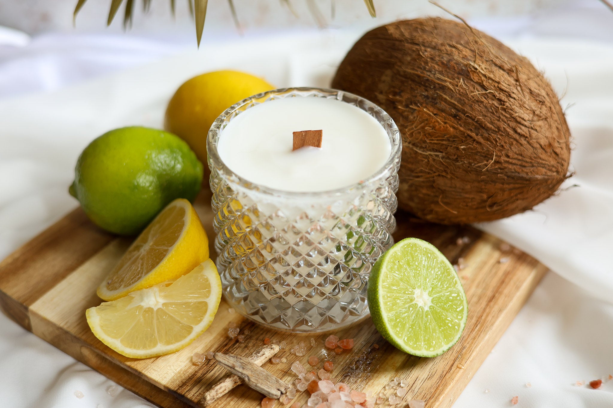 Woodenwick luxury scented candle with coconut, lime, and lemon on a wooden board