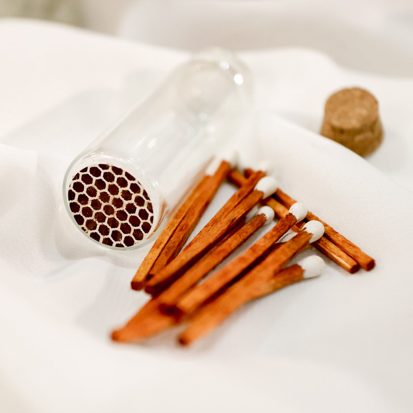 Cute colorful mini matchsticks next to a glass bottle vial with a striker on the bottom on a clean white surface