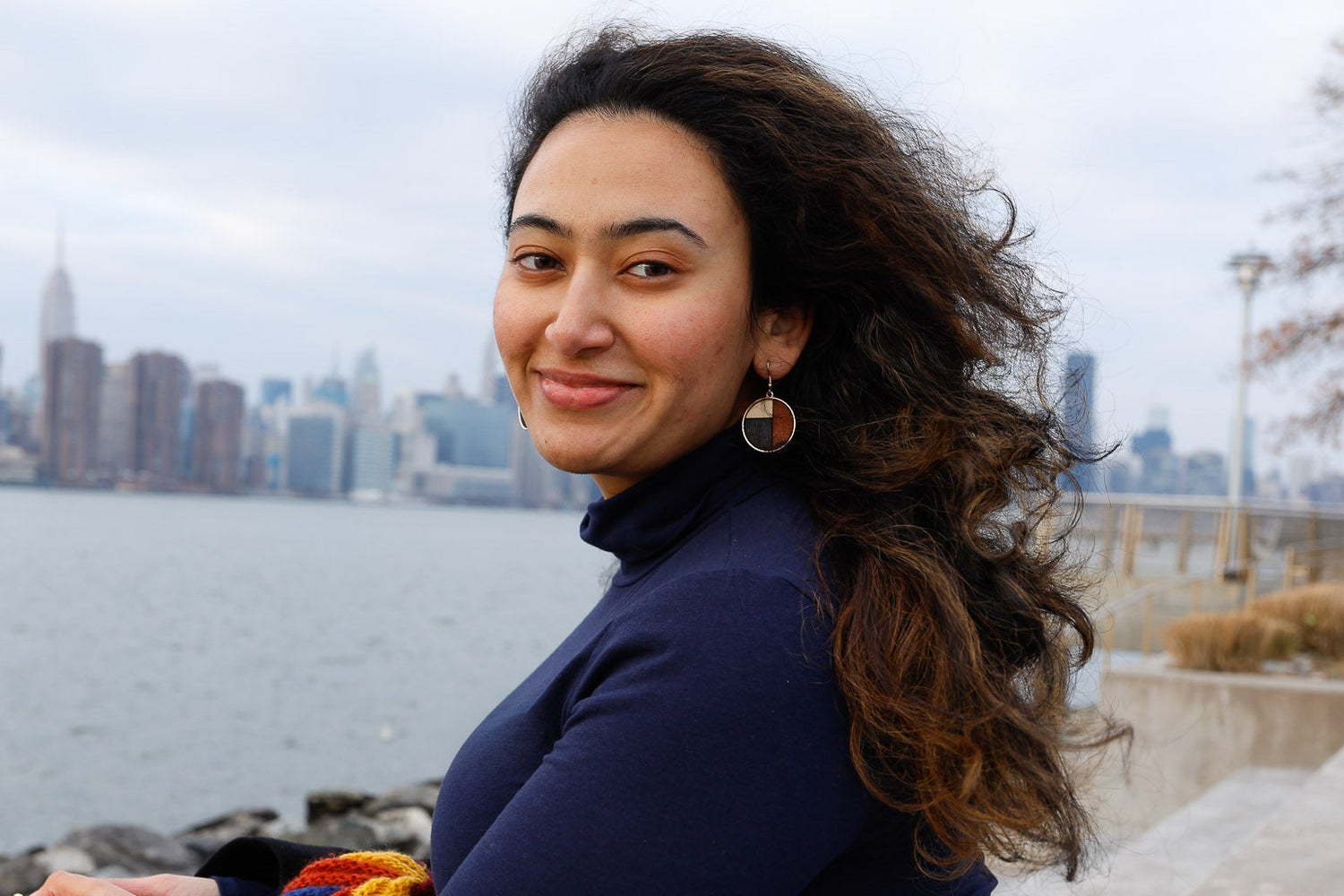Woman sitting by a waterfront with the new york city skyline in the background