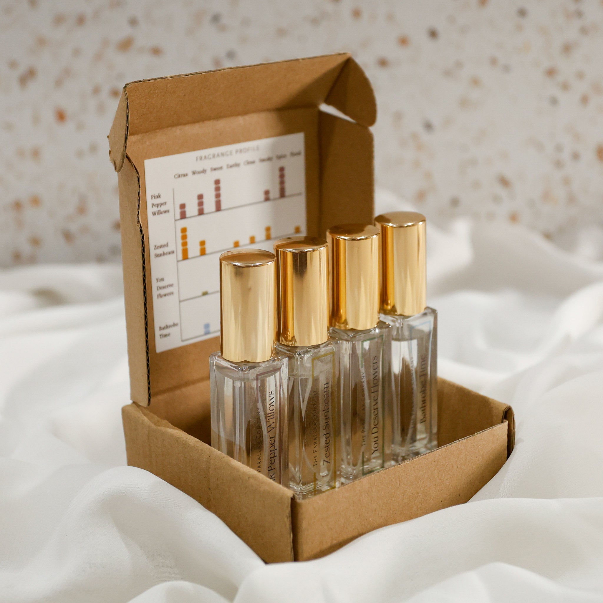 Decorative set of glass travel size perfume bottles with gold caps in a cardboard box on a white neutral background