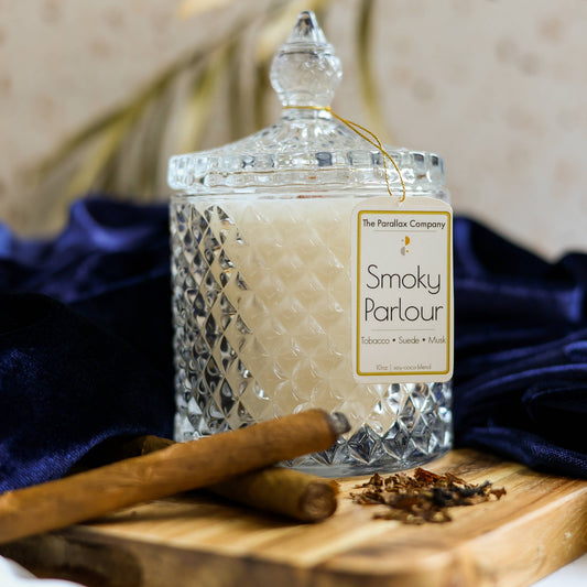 Crystal glass candle on luxurious blue velvet in 'Smoky Parlor' with masculine scents of tobacco suede and musk in front of cigars and embers